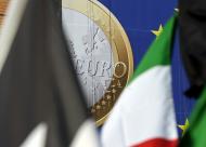 Baner z symbolem euro w tle flag przed siedzibą Komisji Europejskiej Berlaymont w Brukseli.